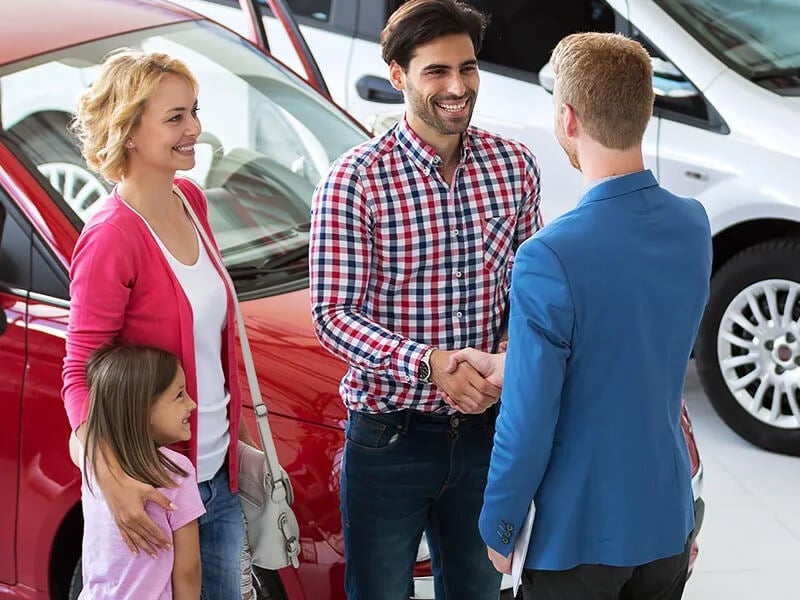Young family in a dealership vehicle showroom